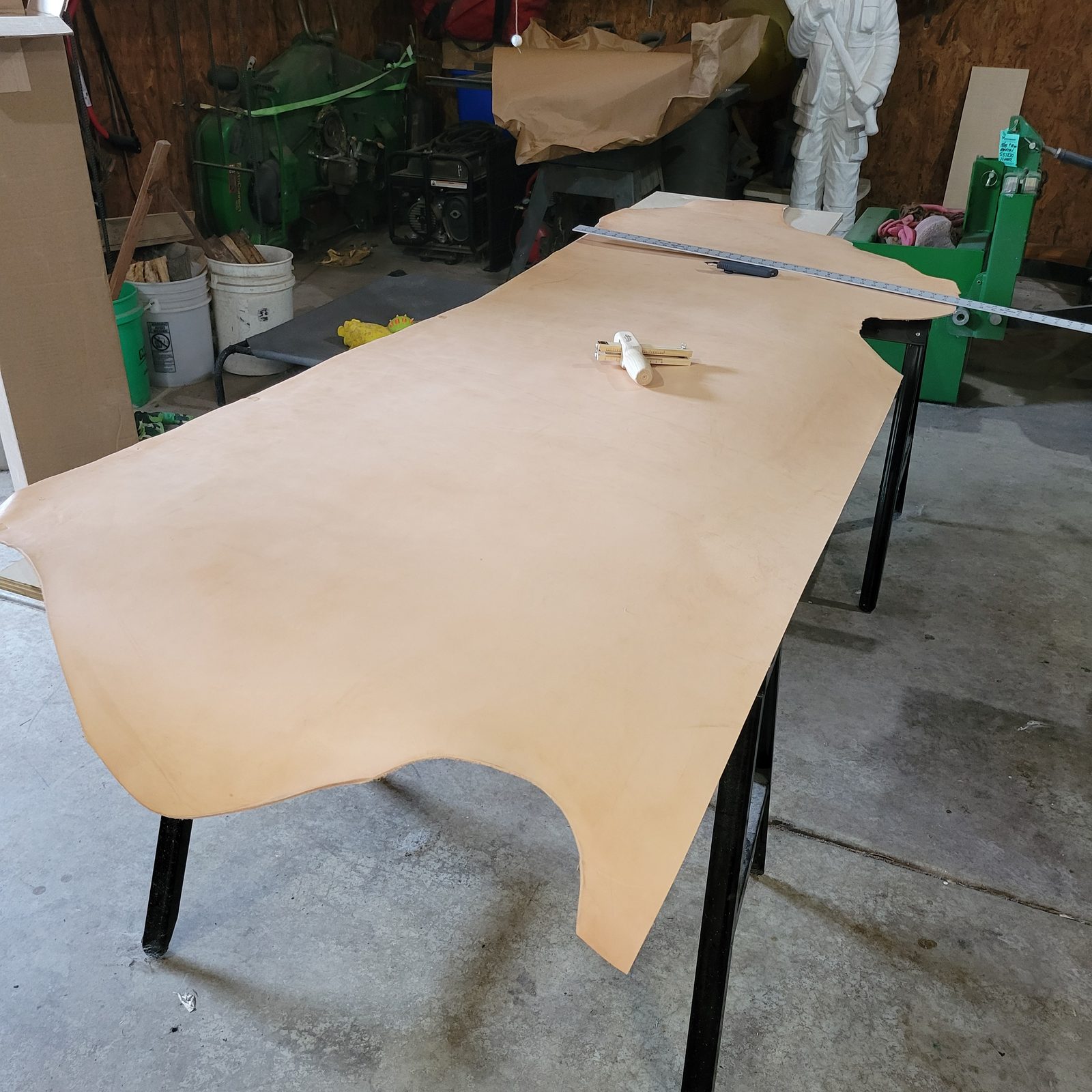 A full side of Hermann Oak veg-tanned leather laid out on the bench with a straightedge